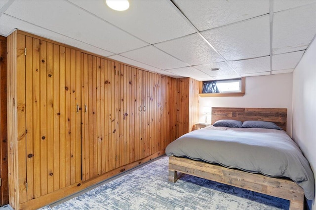 bedroom with wood walls and a drop ceiling