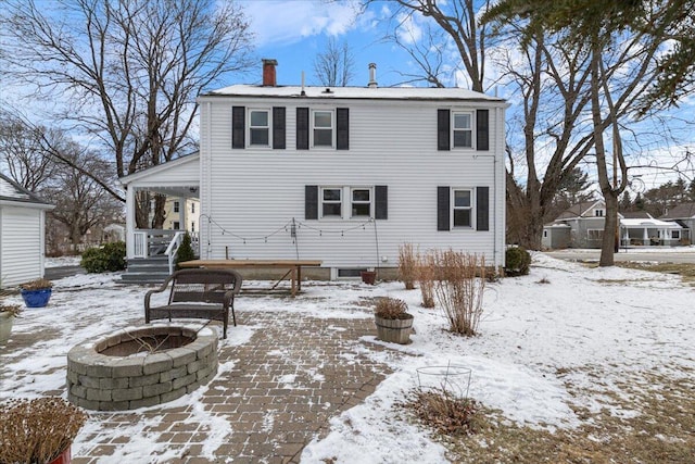 snow covered back of property with a fire pit