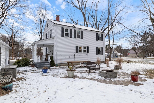 snow covered back of property featuring a fire pit