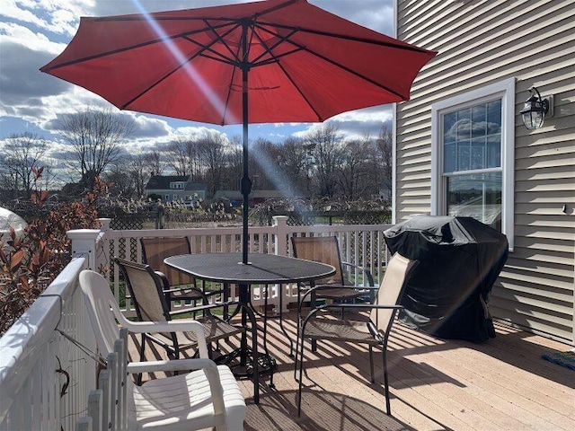 wooden terrace with a grill and outdoor dining area