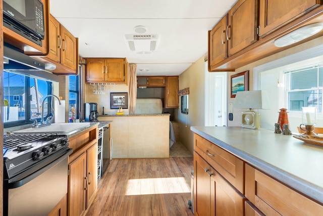 kitchen featuring sink, stainless steel range with gas stovetop, beverage cooler, and light hardwood / wood-style floors