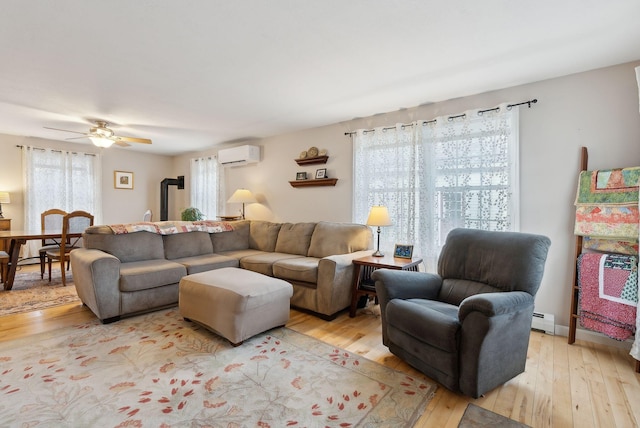 living room featuring a wall mounted air conditioner, light wood-type flooring, baseboard heating, and ceiling fan