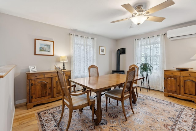 dining area featuring ceiling fan, light hardwood / wood-style floors, and a wall unit AC