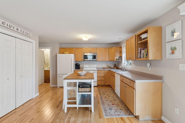 kitchen with sink, light brown cabinets, light hardwood / wood-style flooring, white appliances, and a kitchen island