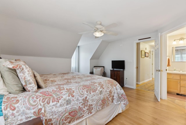 bedroom with ensuite bath, ceiling fan, sink, light hardwood / wood-style floors, and vaulted ceiling