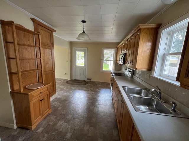 kitchen with stove, decorative light fixtures, crown molding, and sink