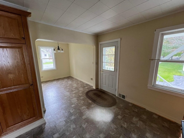 entryway featuring ornamental molding and a notable chandelier