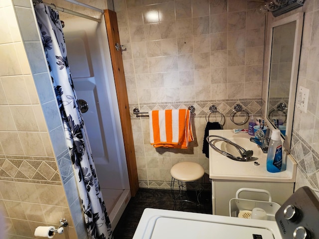 bathroom featuring walk in shower, vanity, and tile walls