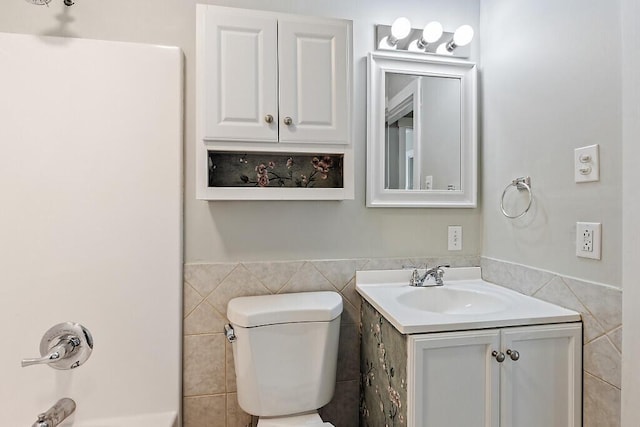 bathroom with vanity, toilet, and tile walls