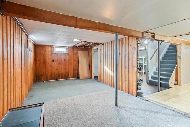 basement featuring light carpet and wooden walls