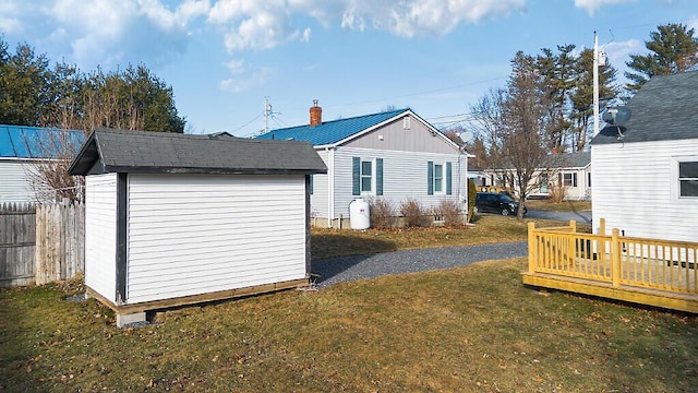 rear view of house with a yard, a deck, and a storage shed