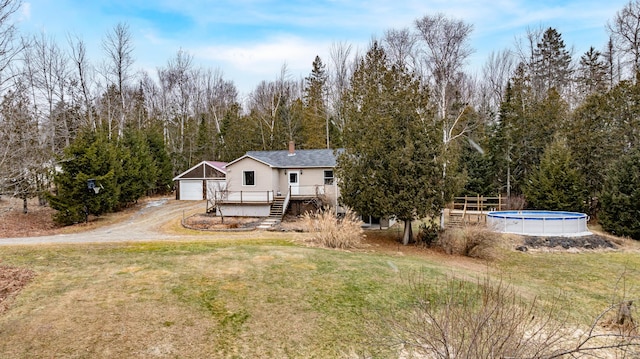 exterior space with a garage, a yard, a swimming pool side deck, and an outbuilding