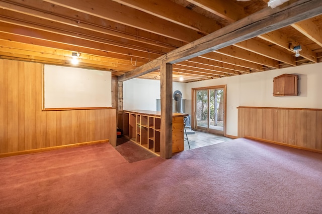 basement featuring light colored carpet and wooden walls