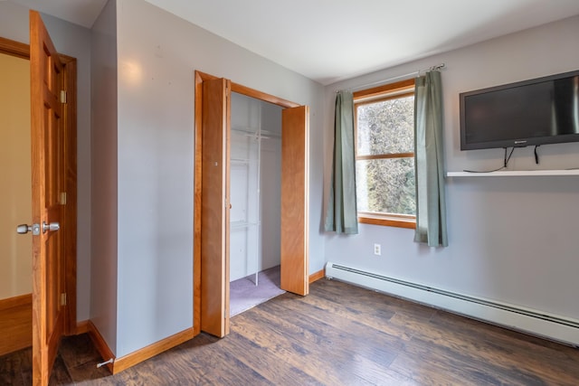 unfurnished bedroom featuring a baseboard radiator, dark hardwood / wood-style floors, and a closet