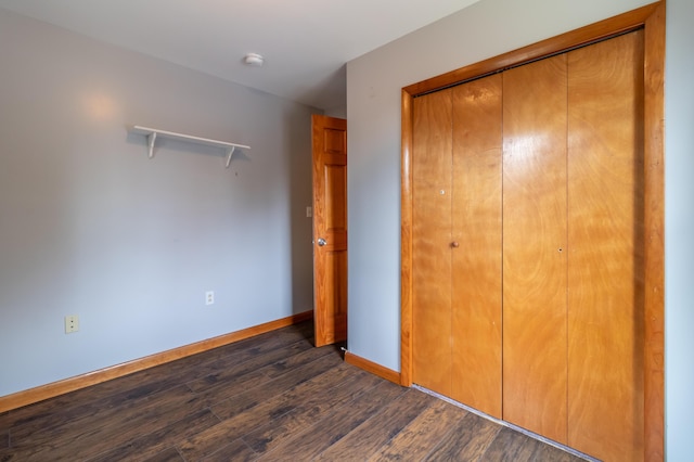 unfurnished bedroom with a closet and dark hardwood / wood-style floors