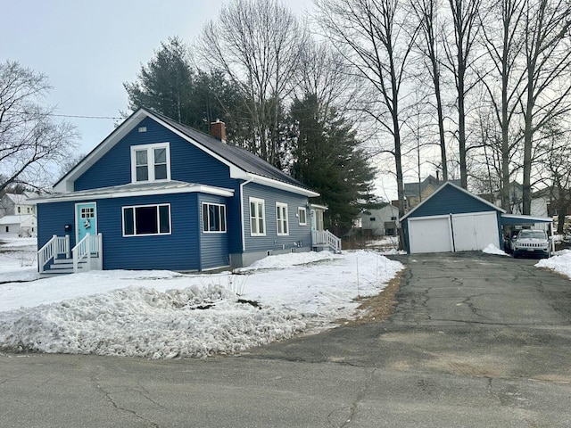 view of snowy exterior with a garage and an outbuilding