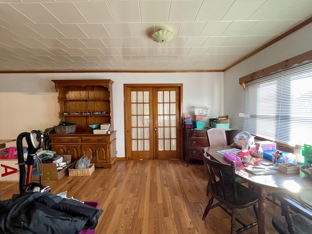 dining room with french doors, ornamental molding, and light wood-type flooring