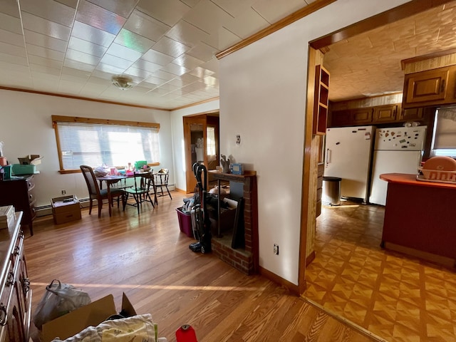 kitchen with white refrigerator, a baseboard radiator, crown molding, and light hardwood / wood-style flooring