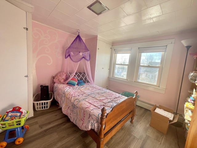 bedroom featuring hardwood / wood-style flooring, ornamental molding, and a baseboard heating unit