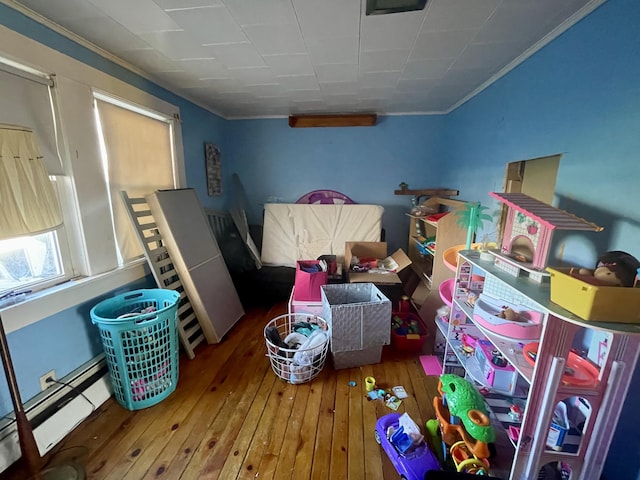 bedroom featuring hardwood / wood-style floors, ornamental molding, and baseboard heating