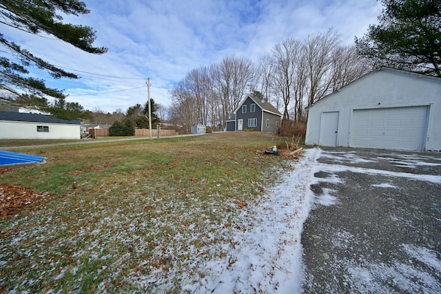 yard covered in snow featuring a garage and an outdoor structure