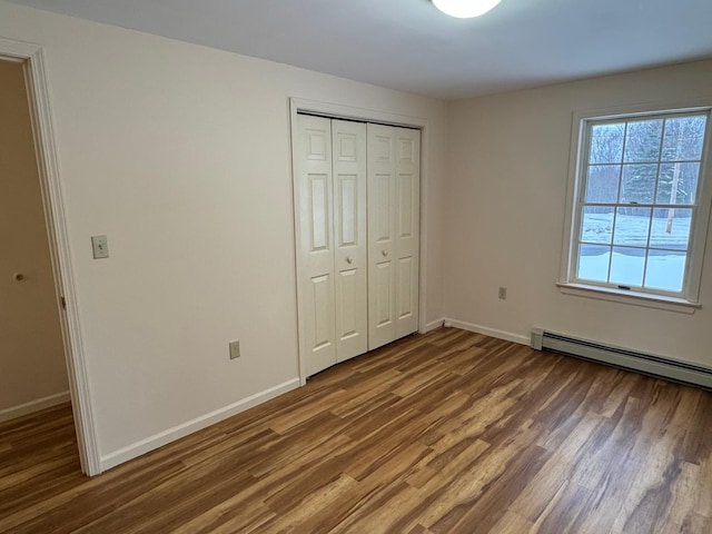 unfurnished bedroom with dark wood-type flooring, a baseboard radiator, and a closet