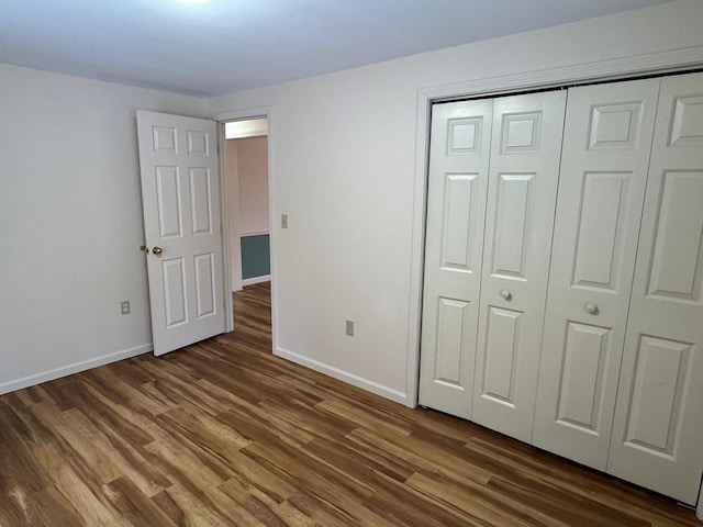 unfurnished bedroom featuring a closet and dark wood-type flooring