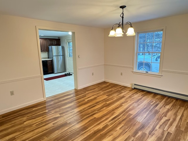 unfurnished room featuring light hardwood / wood-style flooring, a baseboard radiator, and an inviting chandelier