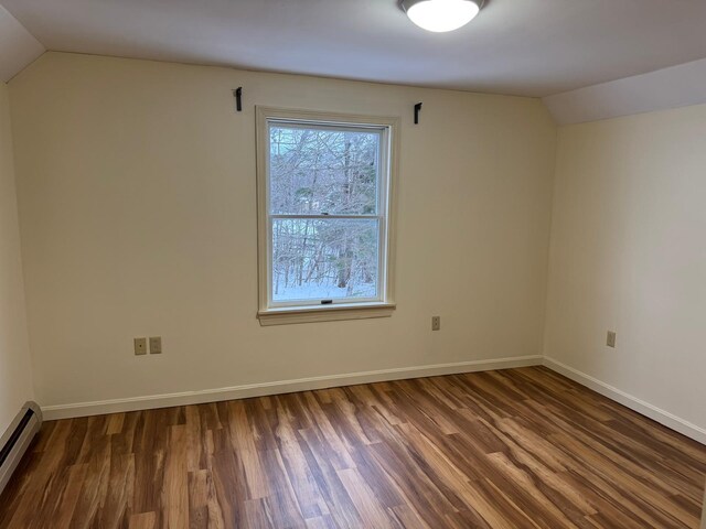 spare room featuring dark hardwood / wood-style floors, lofted ceiling, and a baseboard heating unit