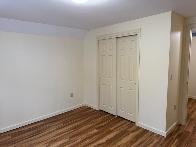 unfurnished bedroom with lofted ceiling, dark wood-type flooring, and a closet