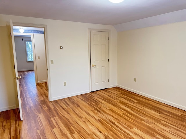 unfurnished room with vaulted ceiling and light wood-type flooring