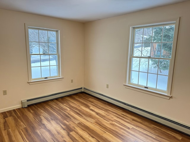 empty room featuring hardwood / wood-style flooring and a baseboard heating unit