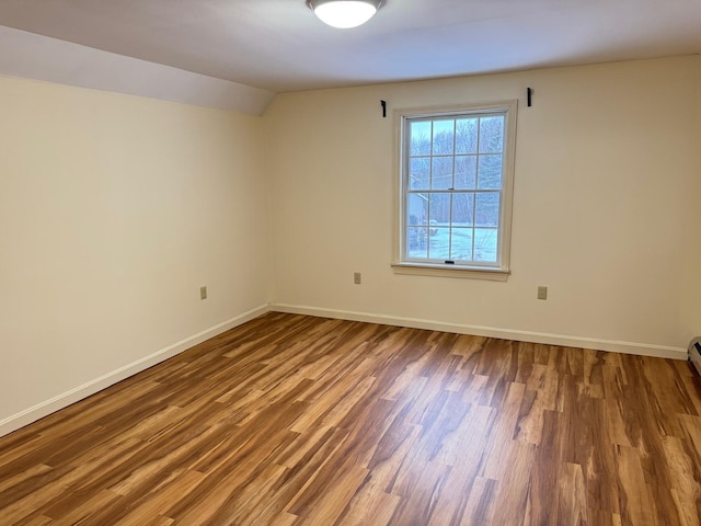 empty room with hardwood / wood-style floors and lofted ceiling