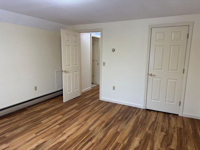 unfurnished bedroom with dark hardwood / wood-style floors and baseboard heating