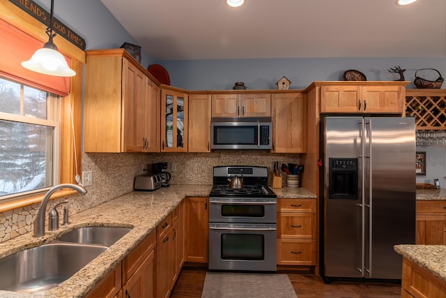 kitchen featuring pendant lighting, sink, backsplash, stainless steel appliances, and light stone countertops