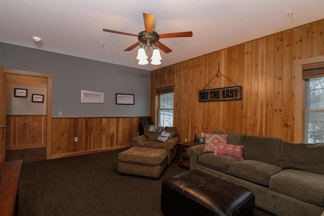 living room with ceiling fan, wooden walls, and a healthy amount of sunlight