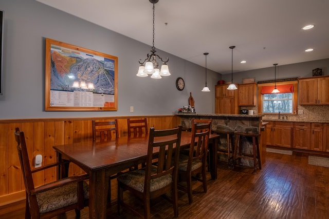 dining space with dark hardwood / wood-style flooring, sink, and wood walls