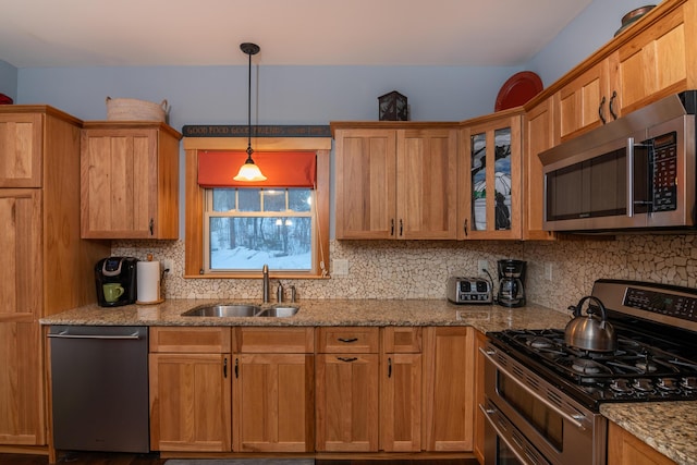 kitchen featuring sink, light stone counters, tasteful backsplash, hanging light fixtures, and stainless steel appliances