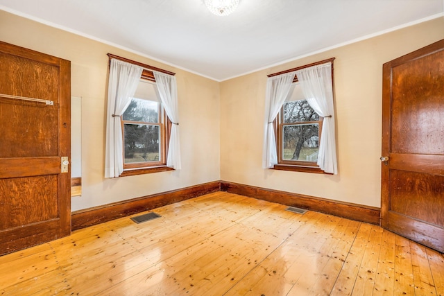 spare room featuring light hardwood / wood-style floors and crown molding