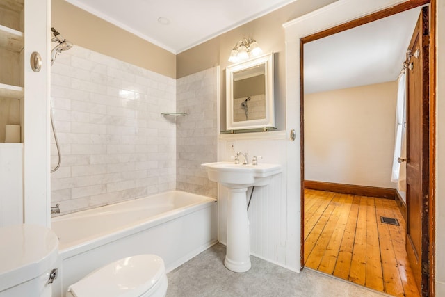 bathroom featuring toilet and tiled shower / bath