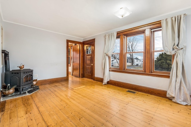 living room featuring light hardwood / wood-style floors, a wood stove, and ornamental molding