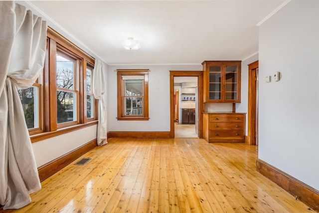 empty room with crown molding and light hardwood / wood-style floors