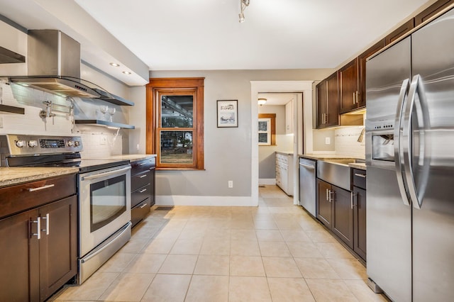 kitchen featuring dark brown cabinetry, appliances with stainless steel finishes, tasteful backsplash, light stone counters, and light tile patterned floors