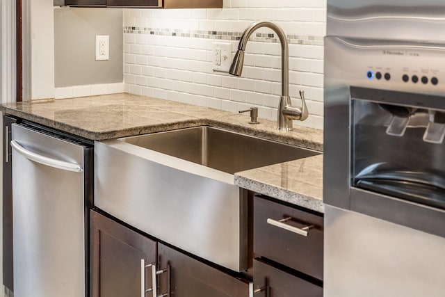 kitchen featuring sink, light stone counters, decorative backsplash, and dark brown cabinetry