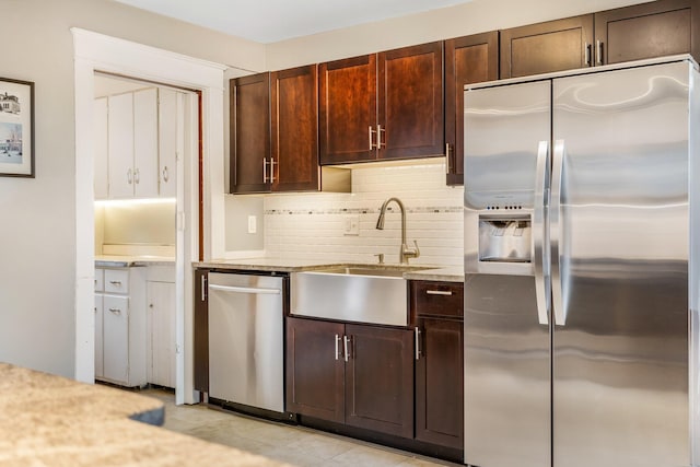 kitchen featuring decorative backsplash, sink, stainless steel appliances, and light stone countertops