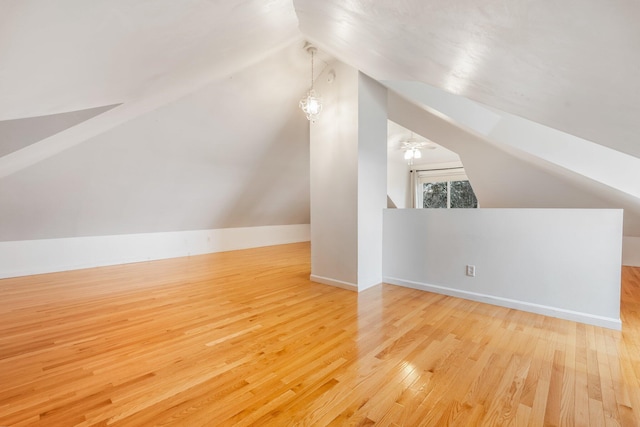 bonus room with light wood-type flooring and vaulted ceiling