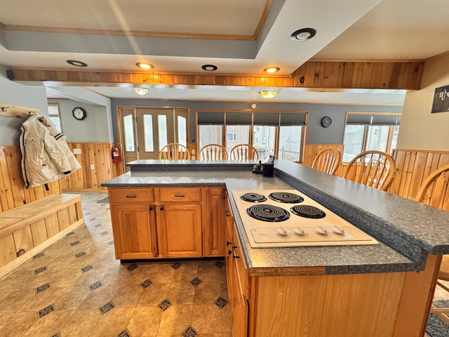 kitchen with wood walls, a center island, a kitchen bar, light tile patterned floors, and white electric stovetop