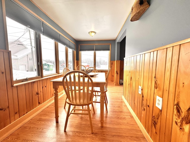 dining area featuring light hardwood / wood-style flooring, wooden walls, and a baseboard radiator