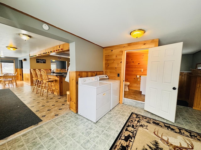 laundry area with bar area, independent washer and dryer, and wooden walls