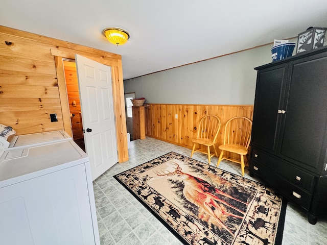 clothes washing area with washer and dryer and wooden walls